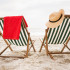 Straw hat and towel kept on beach chairs
